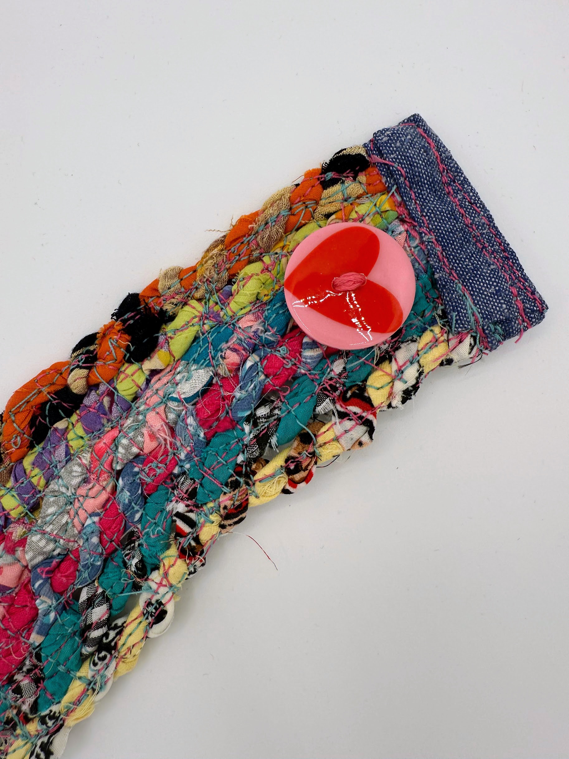 Close-up of braided fabric, visible stitching and pink heart button