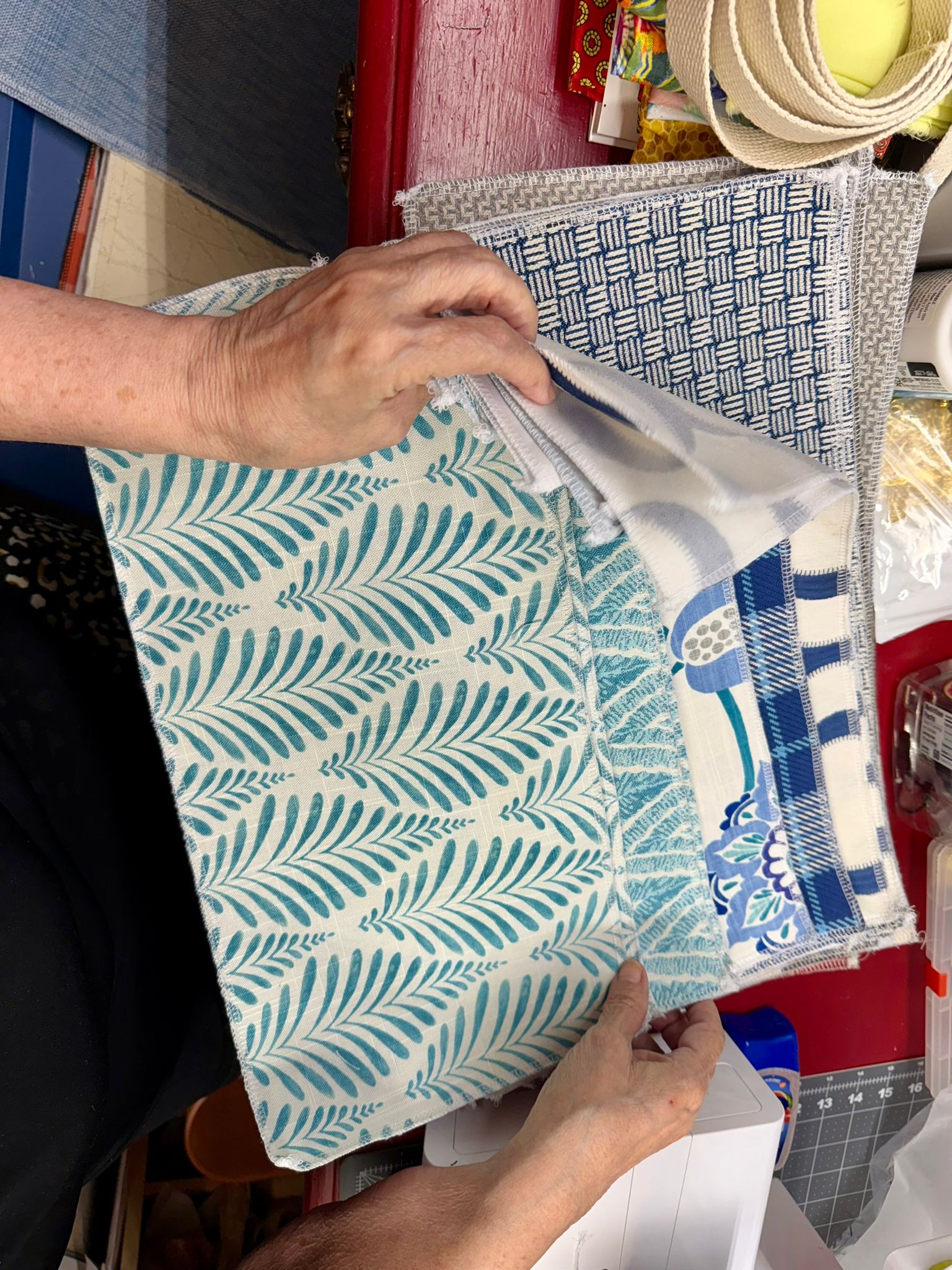 Hands examining blue and white textile samples